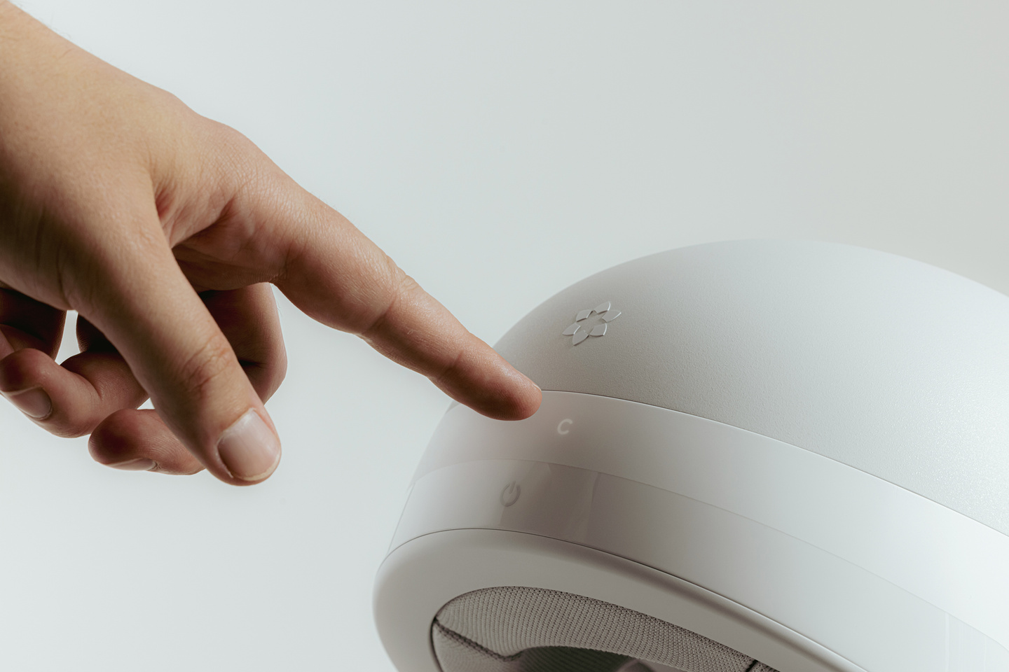 Finger interacting with touch controls on the upper surface of a white wearable device