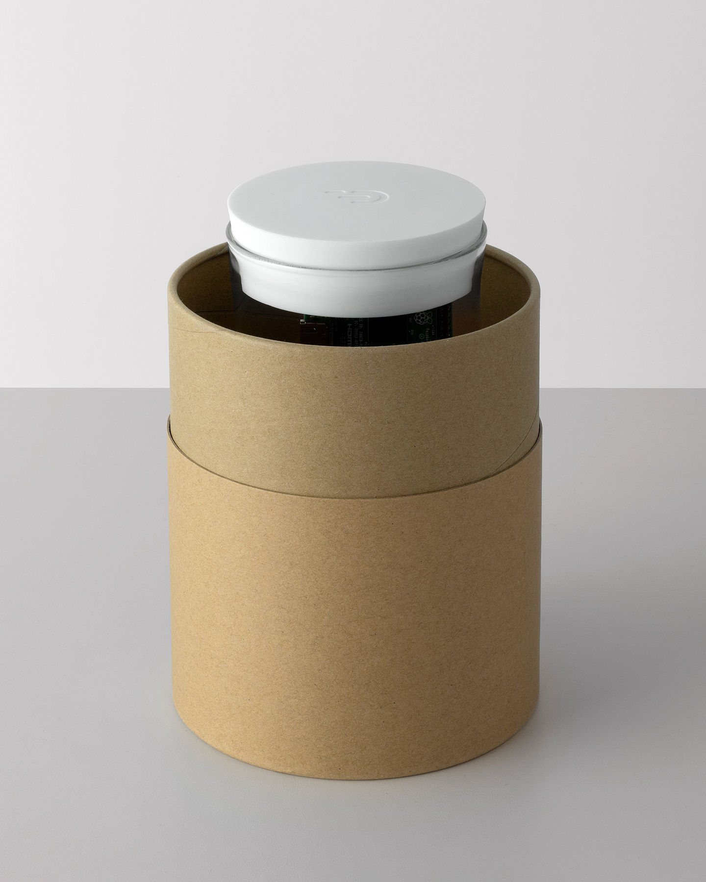 Front view of open cylindrical cardboard container with the Dadi Founding Node inside.