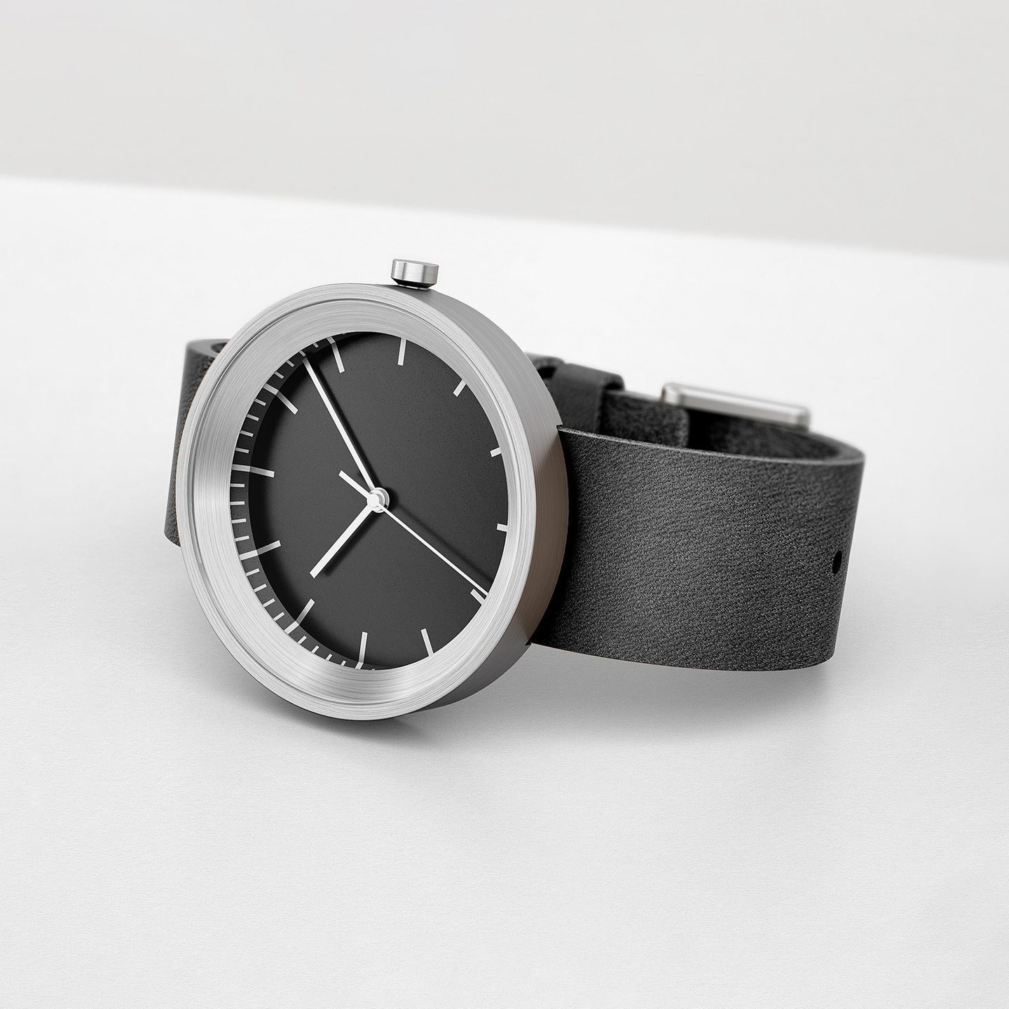 Round metallic wristwatch with black dial and leather strap on a white background