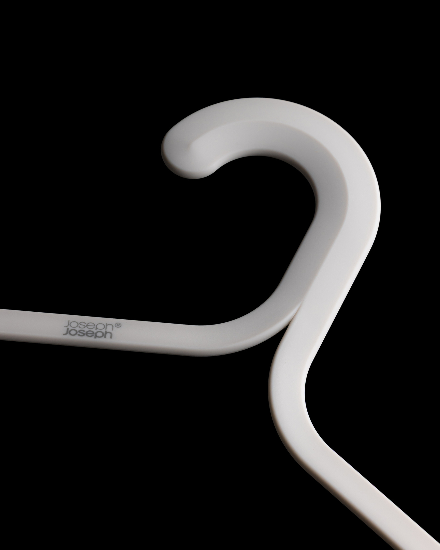Profile view of a white coat hanger neck hook against a black background