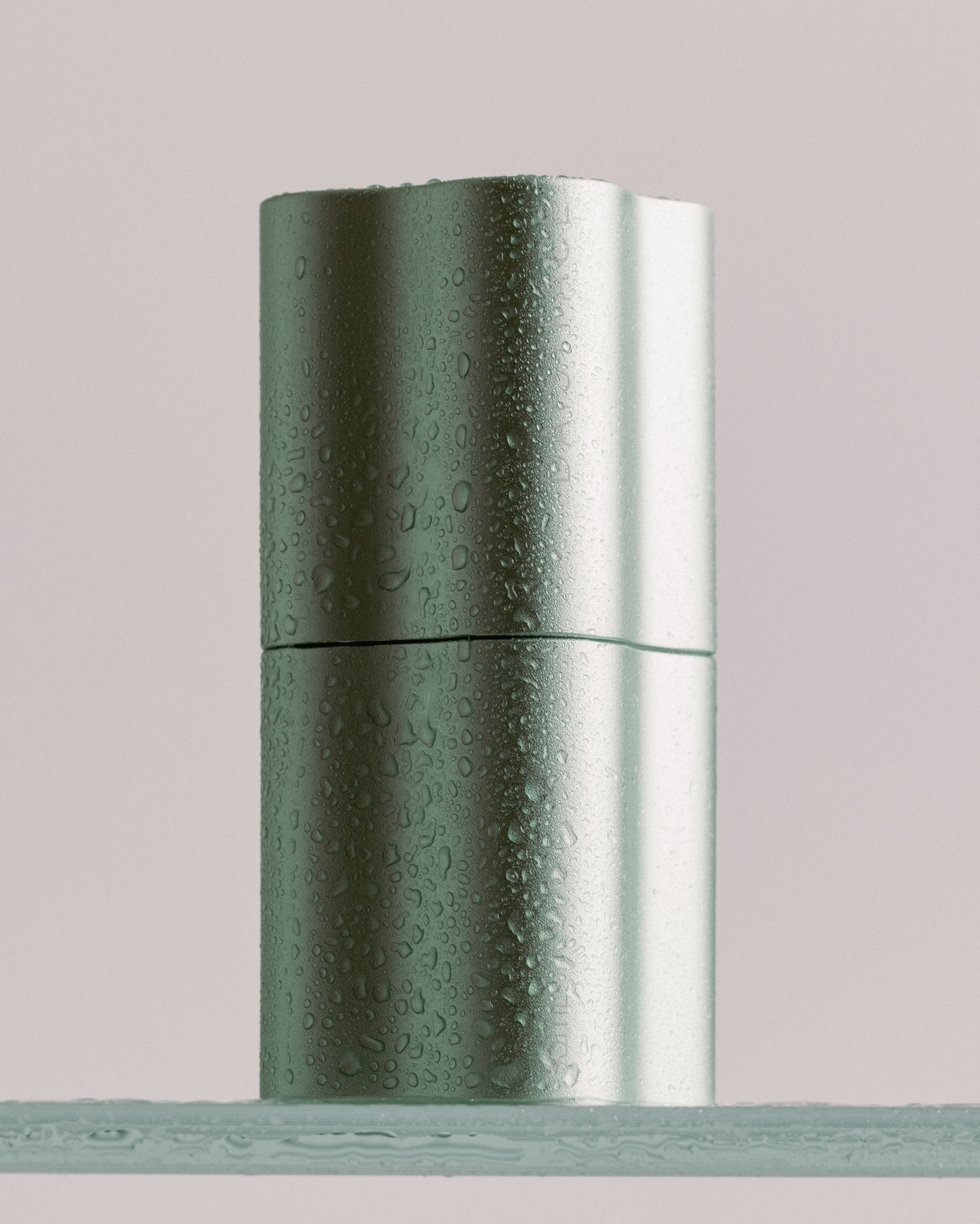 Light green fluted skincare bottle standing on a grey surface