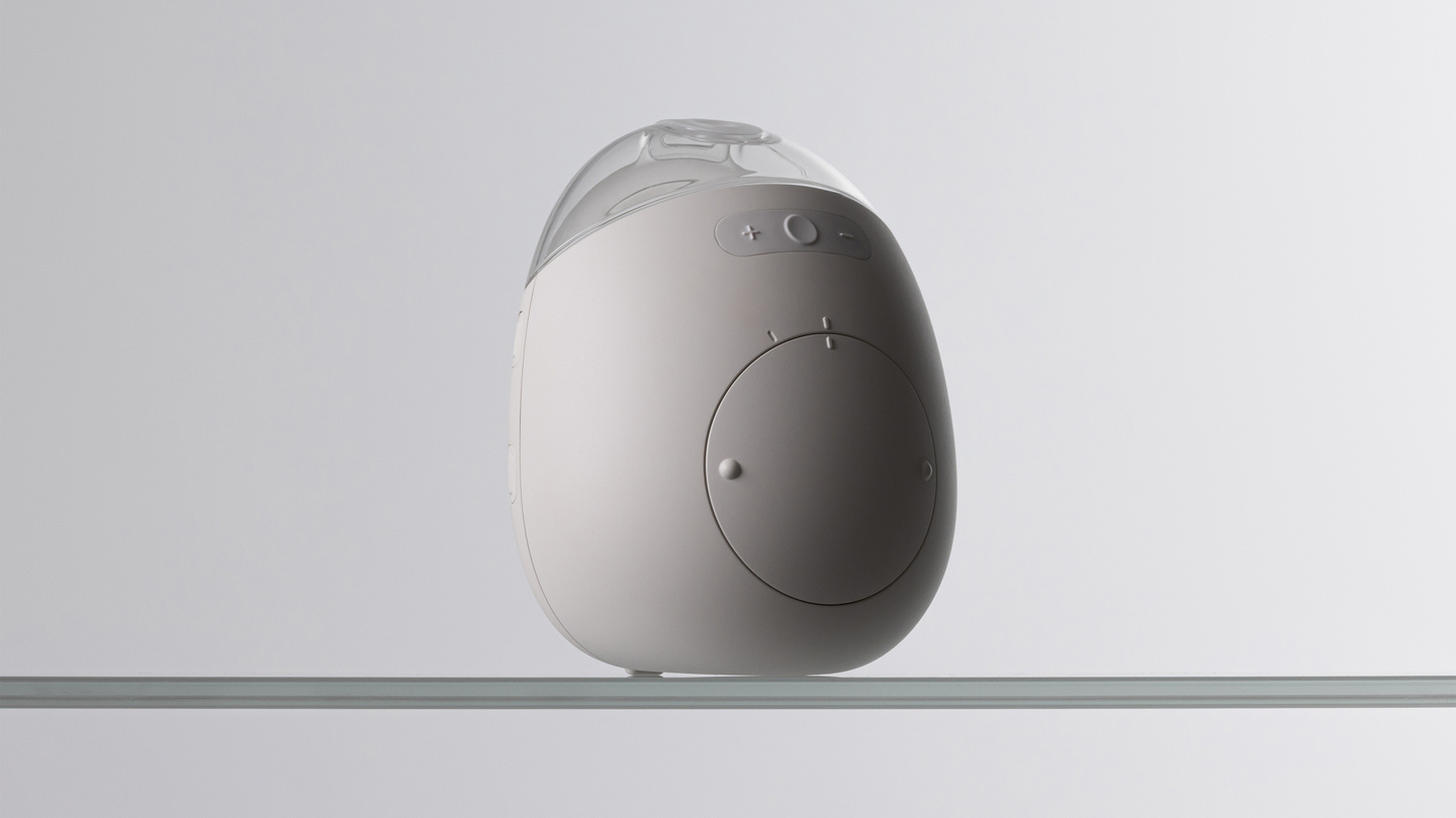 Studio shot of the white Avira wearable breast pump unit resting on a light surface.