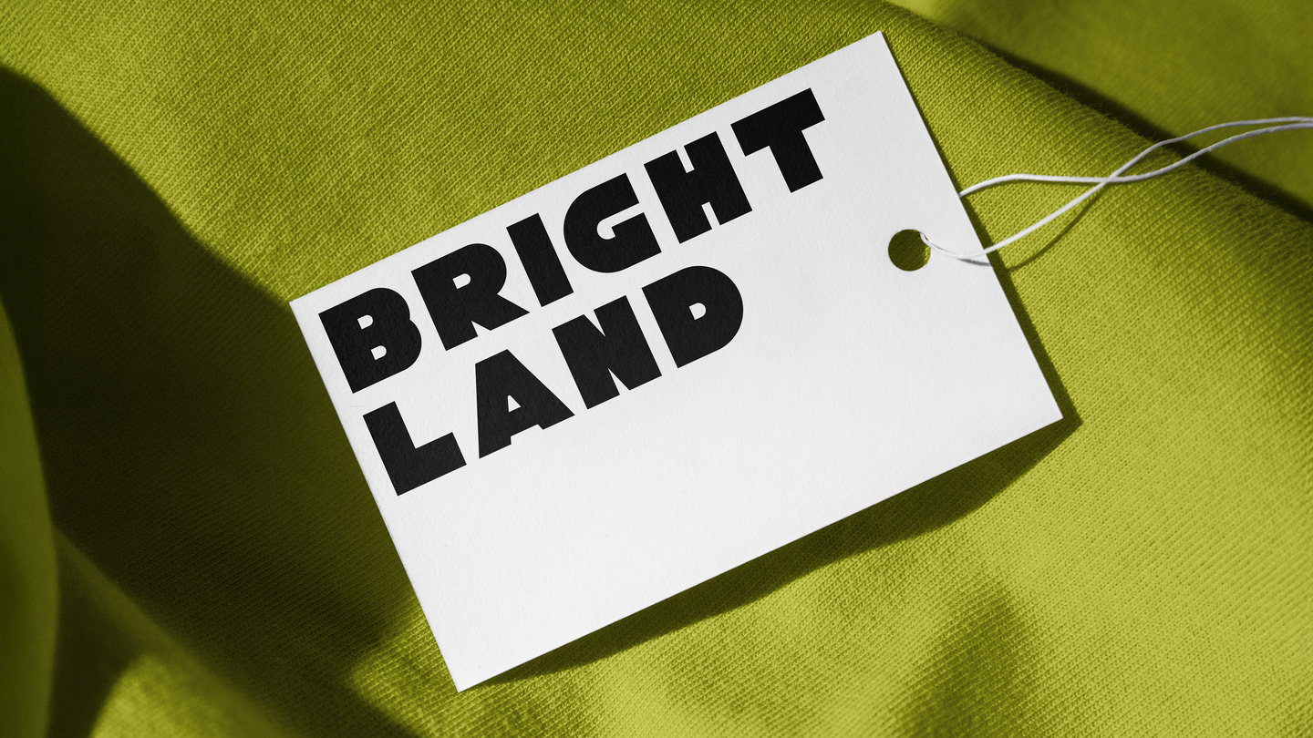 Printed white Brightland swing tag attached to green textured fabric.