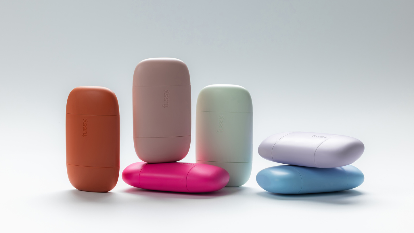Six colorful pebble-shaped Fussy deodorant cases standing on a light background.