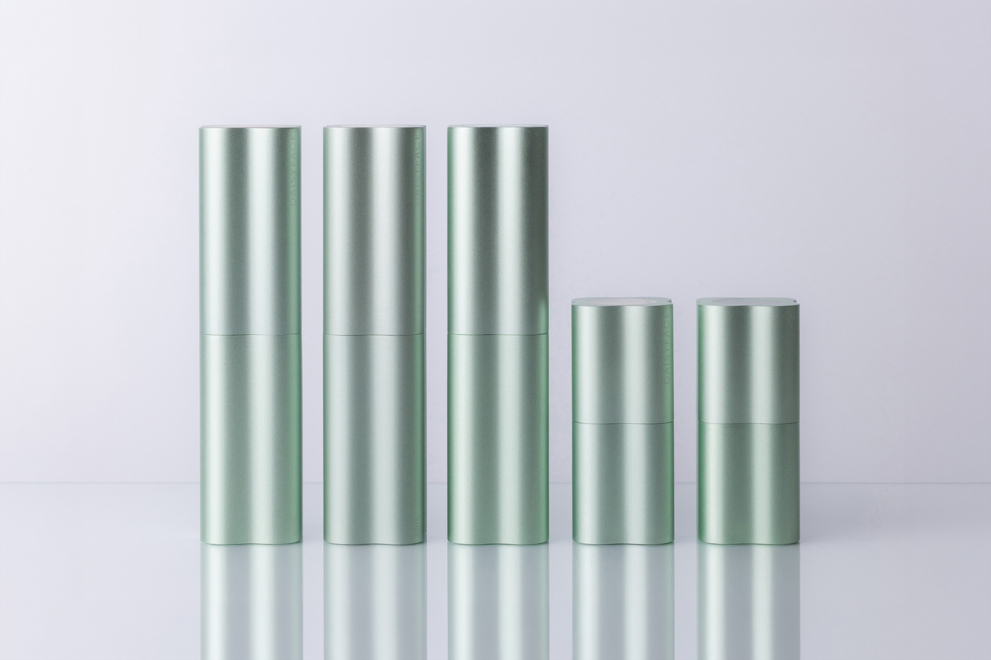 Five light green fluted skincare bottles arranged side by side