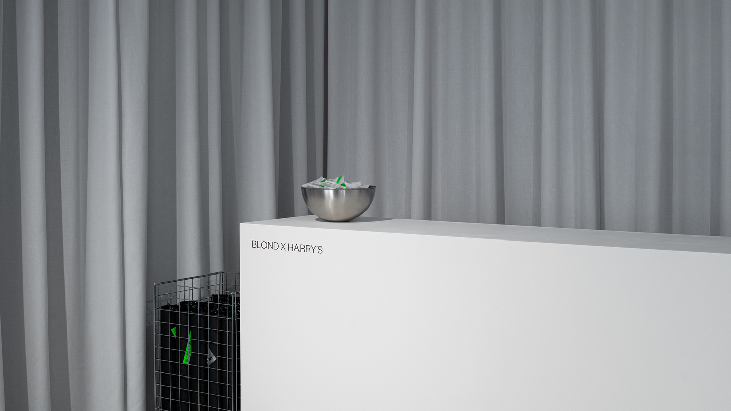 Minimalist white reception counter set against a grey curtain backdrop in an exhibition space