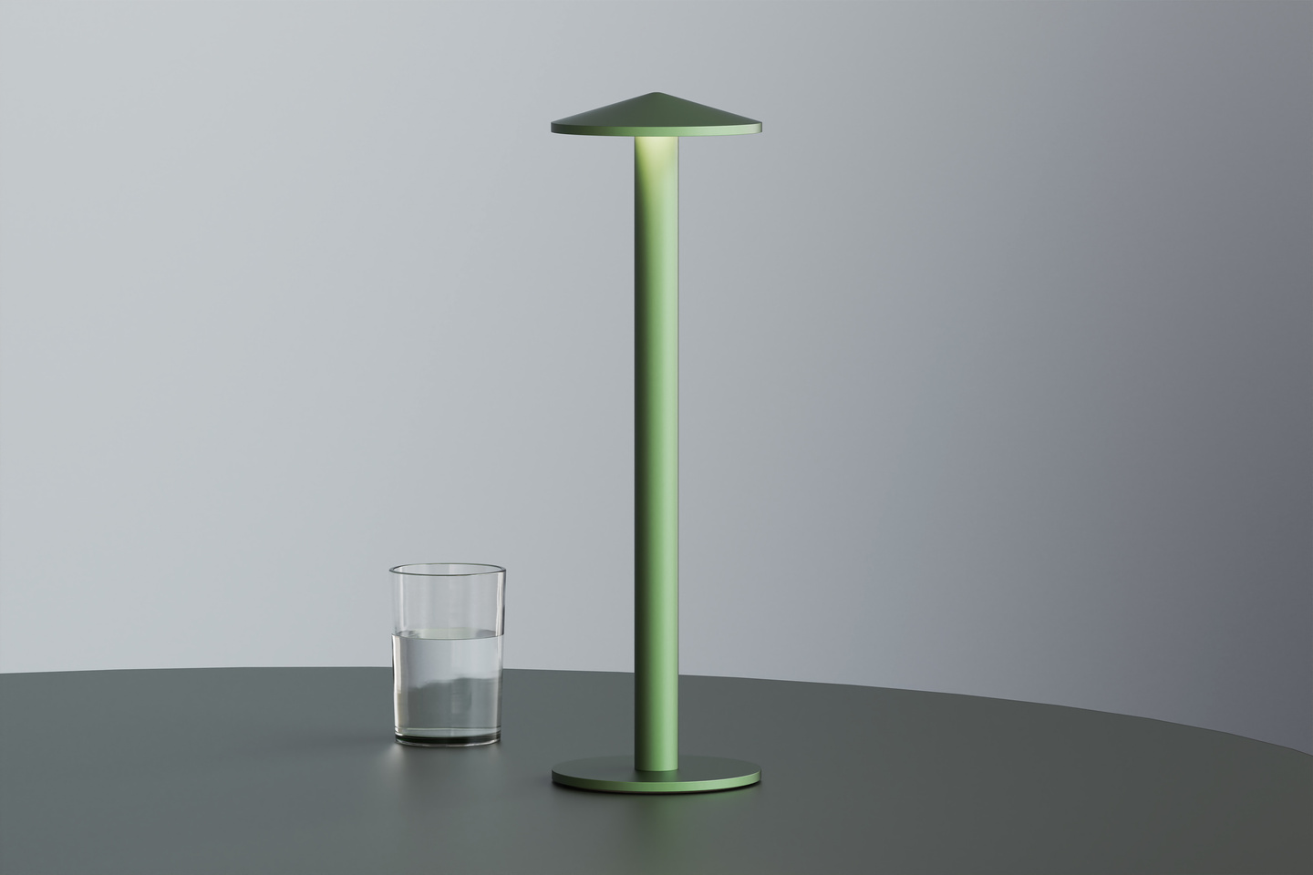 Green Parasol Lamp standing next to a water glass on a table.