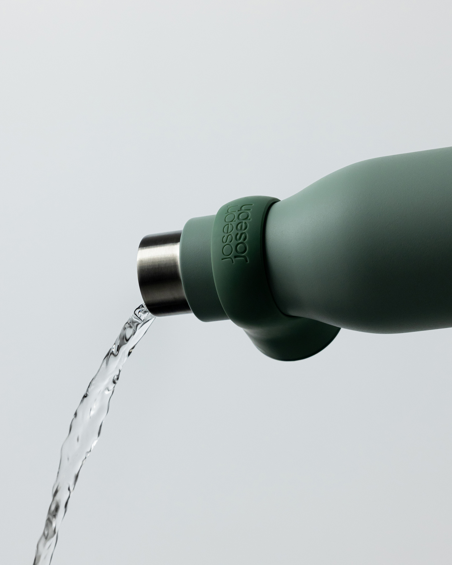 Water stream pouring from a green reusable water bottle