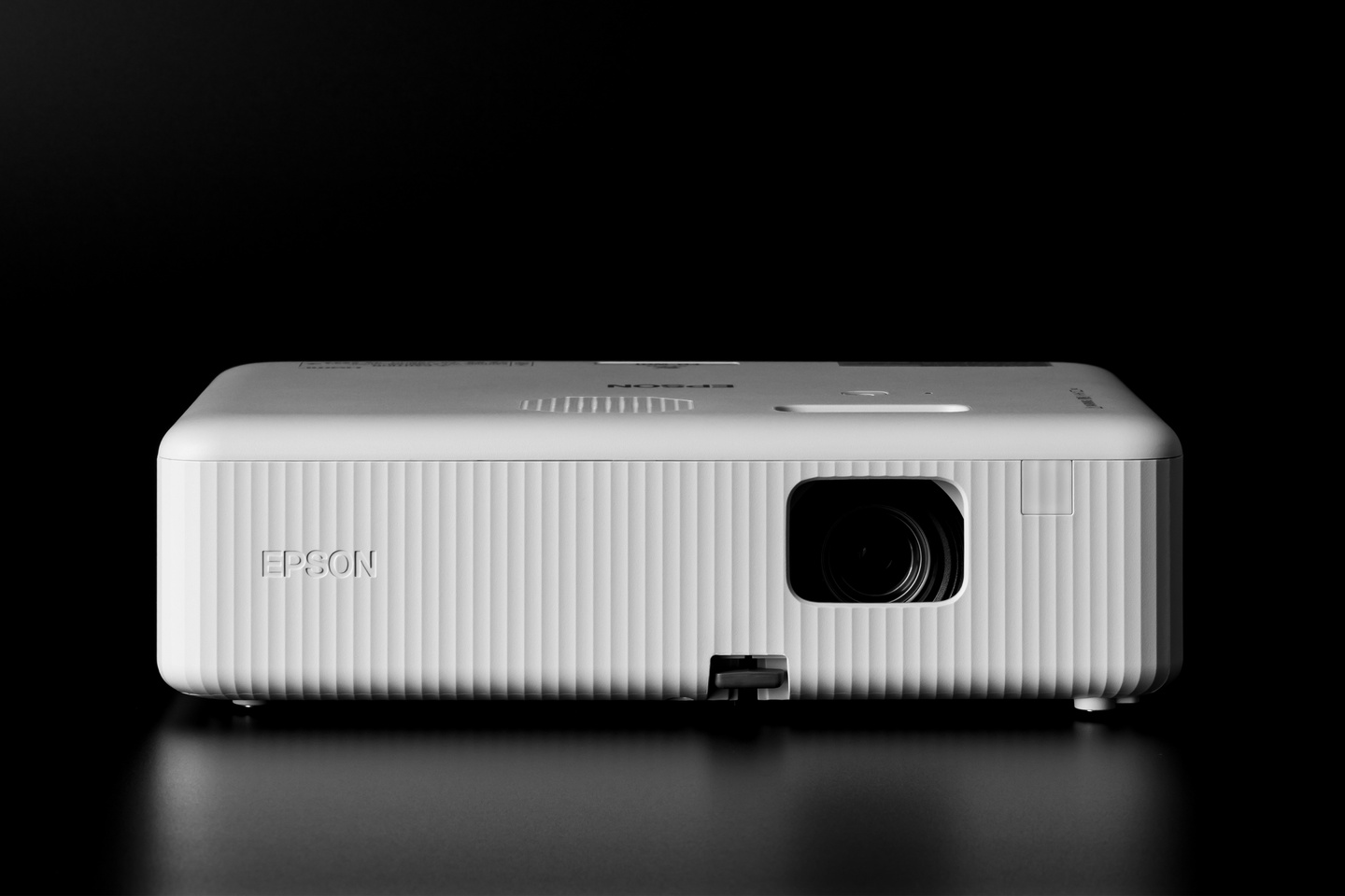 Distant front view of a white home projector on dark background