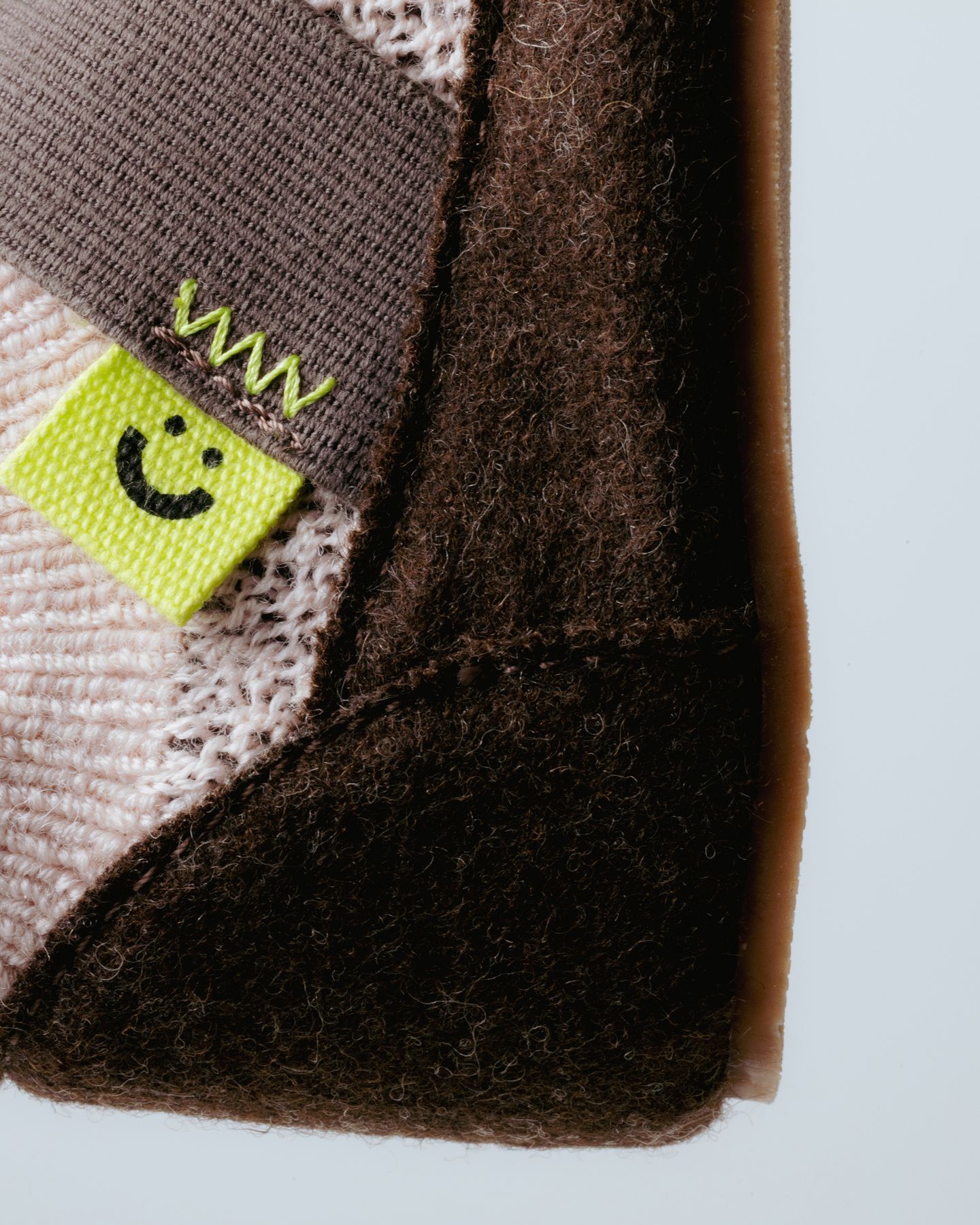 Close-up of dark woven shoe fabric with a yellow smiley brand tag.