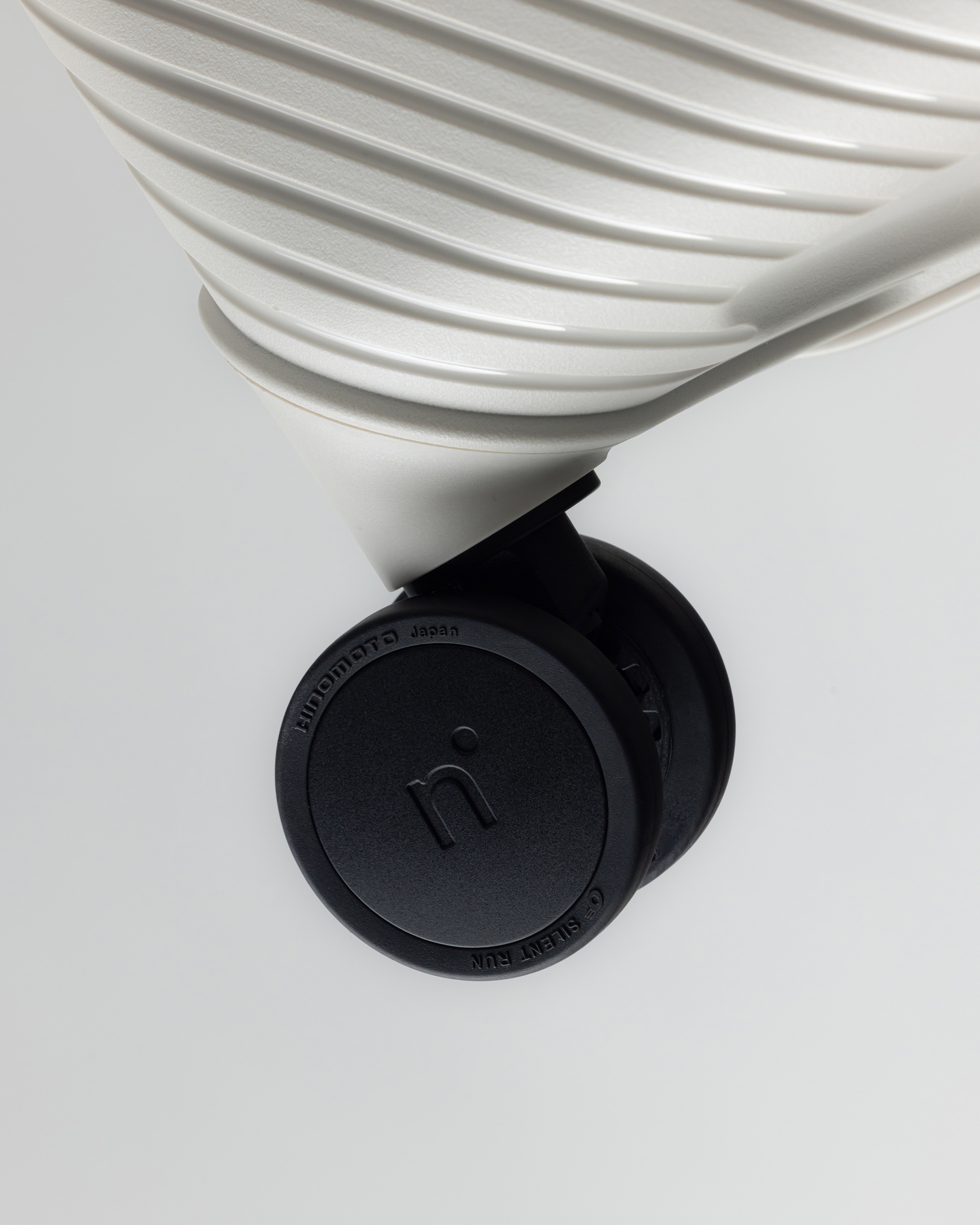 Close-up of a black caster wheel attached to a grey suitcase base