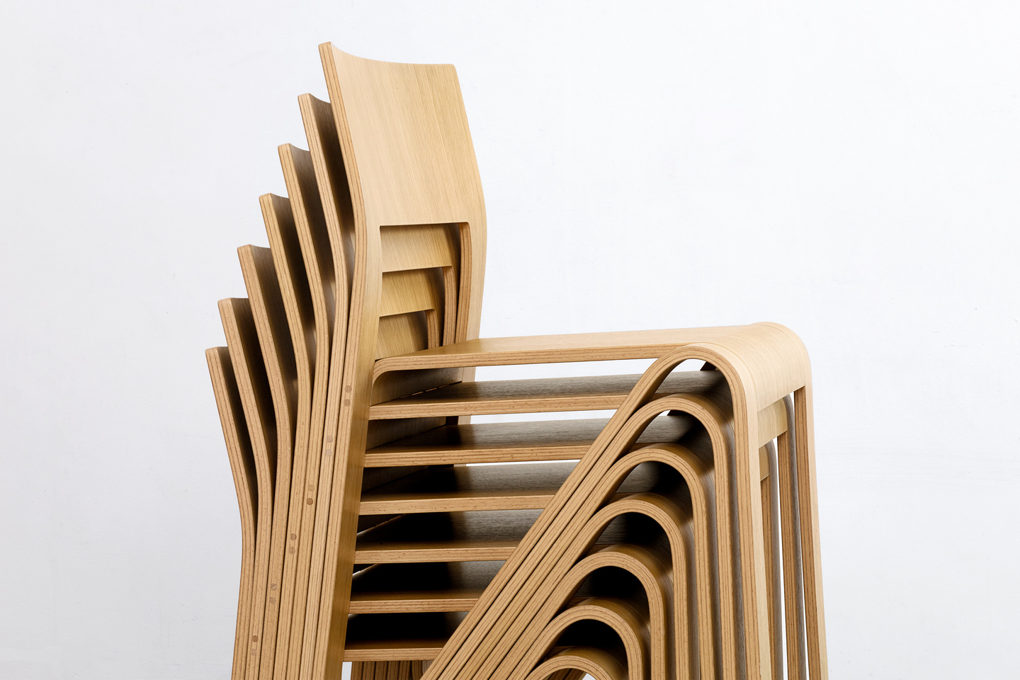 Detailed close-up showing the precise nesting and stacking of bent plywood chair frames.