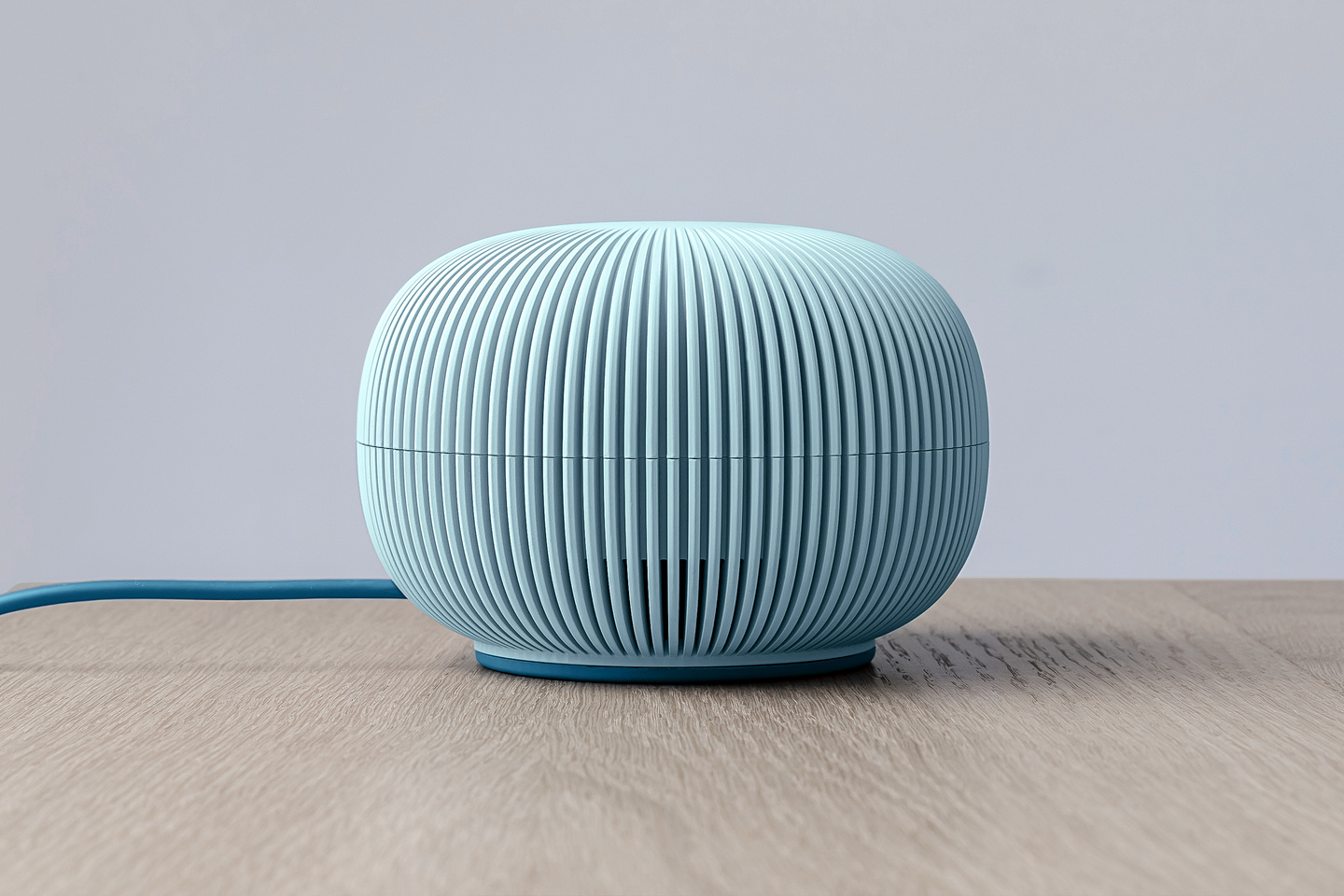 Ribbed light-blue spherical Zobi Hedgehog device resting on a light wooden surface