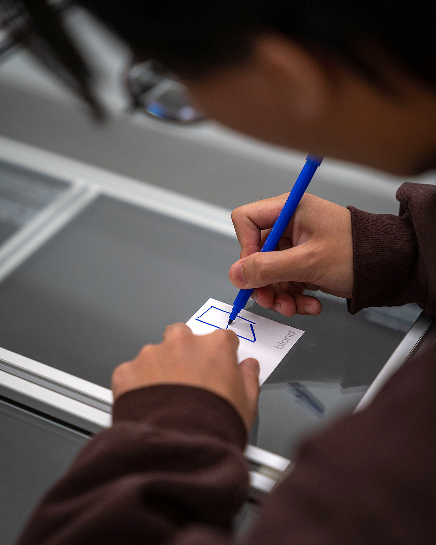 Close-up of a person writing notes on a small white card.