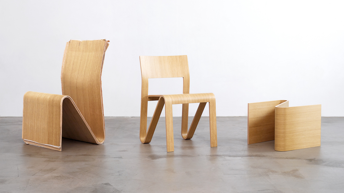 Three wooden chairs and stools made from plywood arranged on a concrete floor.
