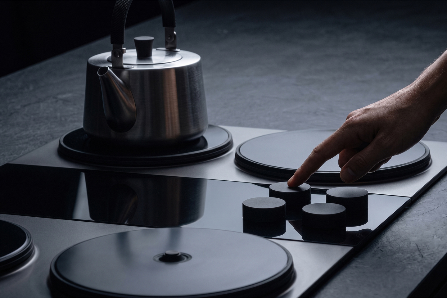 Stainless steel kettle resting on a dark induction stovetop burner