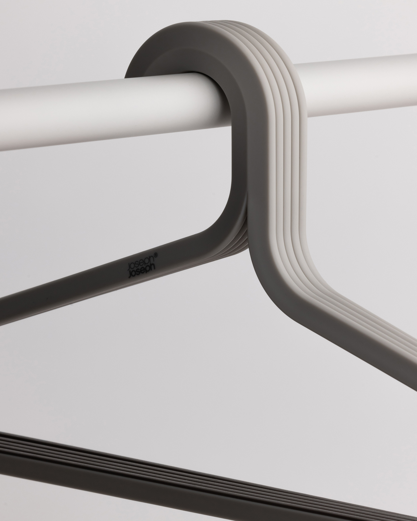 Detail view of a grey coat hanger neck hooked onto a wardrobe rail