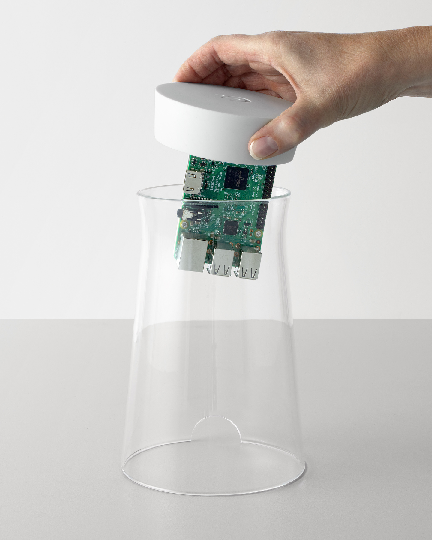 Hand lifting the top white housing with electronics out of a glass cylinder.