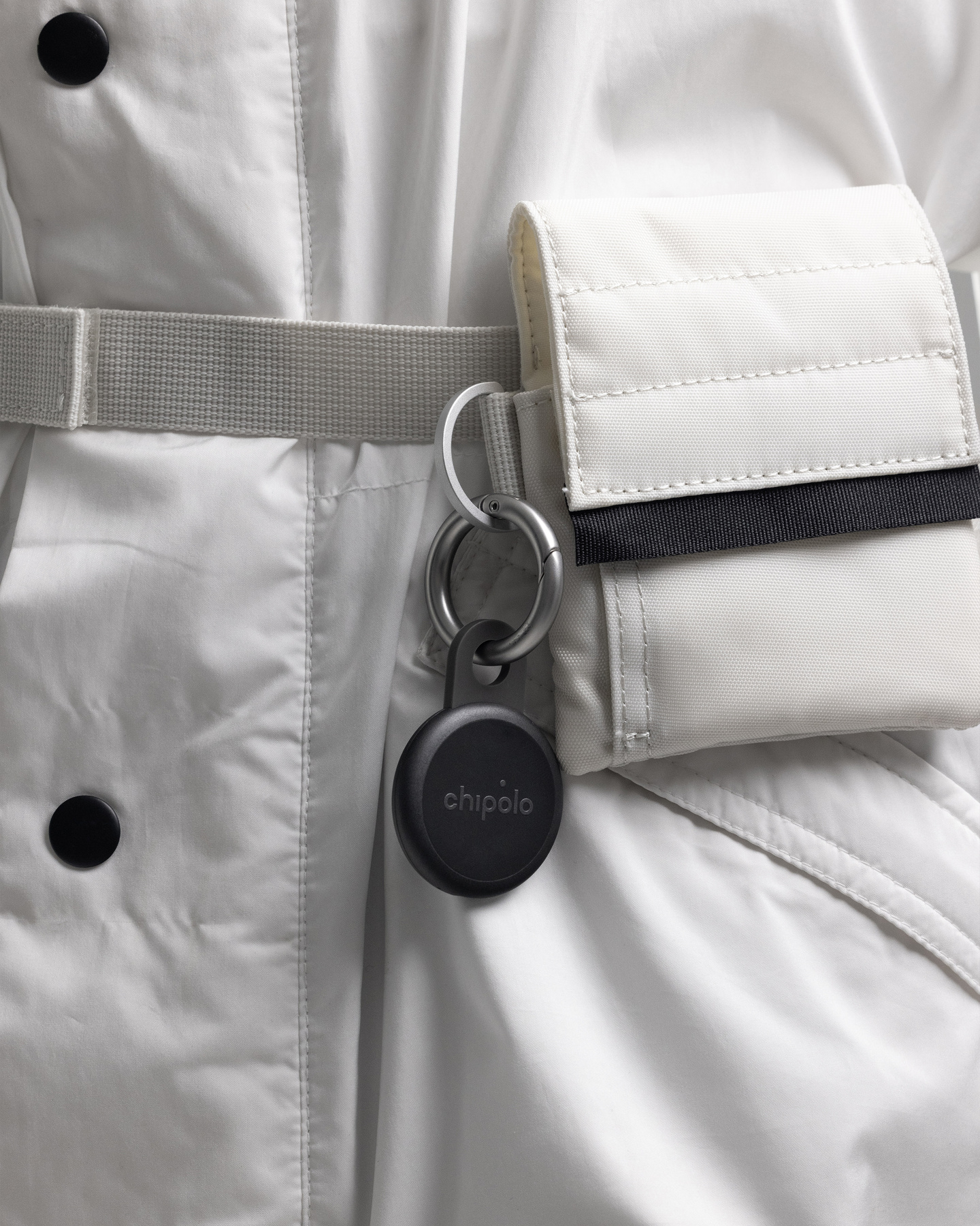 Close-up of a small black tracker attached to a metal key ring.