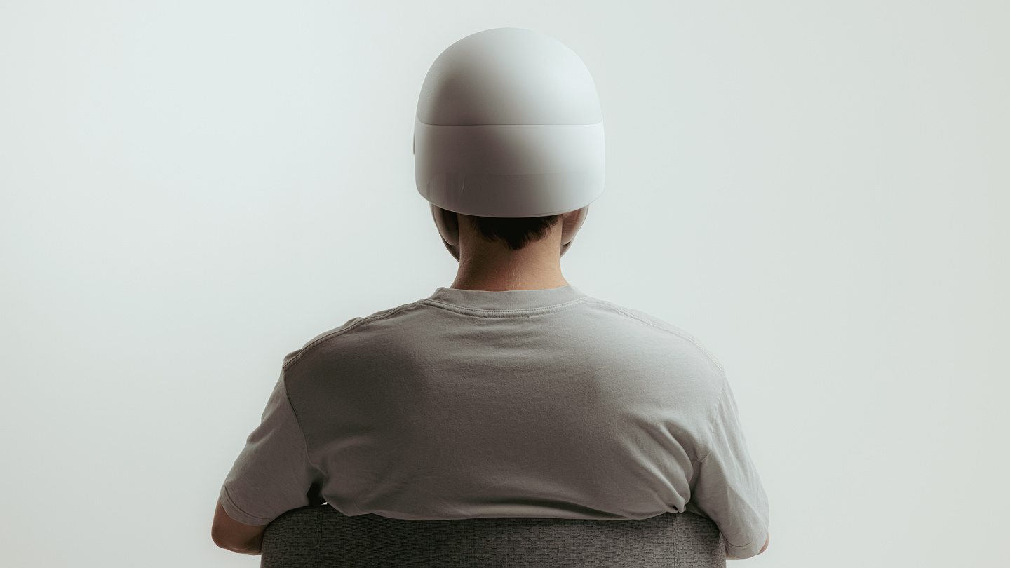 Person from behind wearing white medical headwear sat in a chair