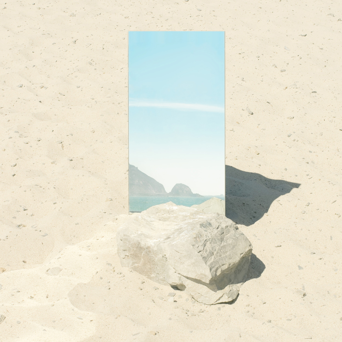 Blue mirror object on a sandy beach in front of sand coloured stones