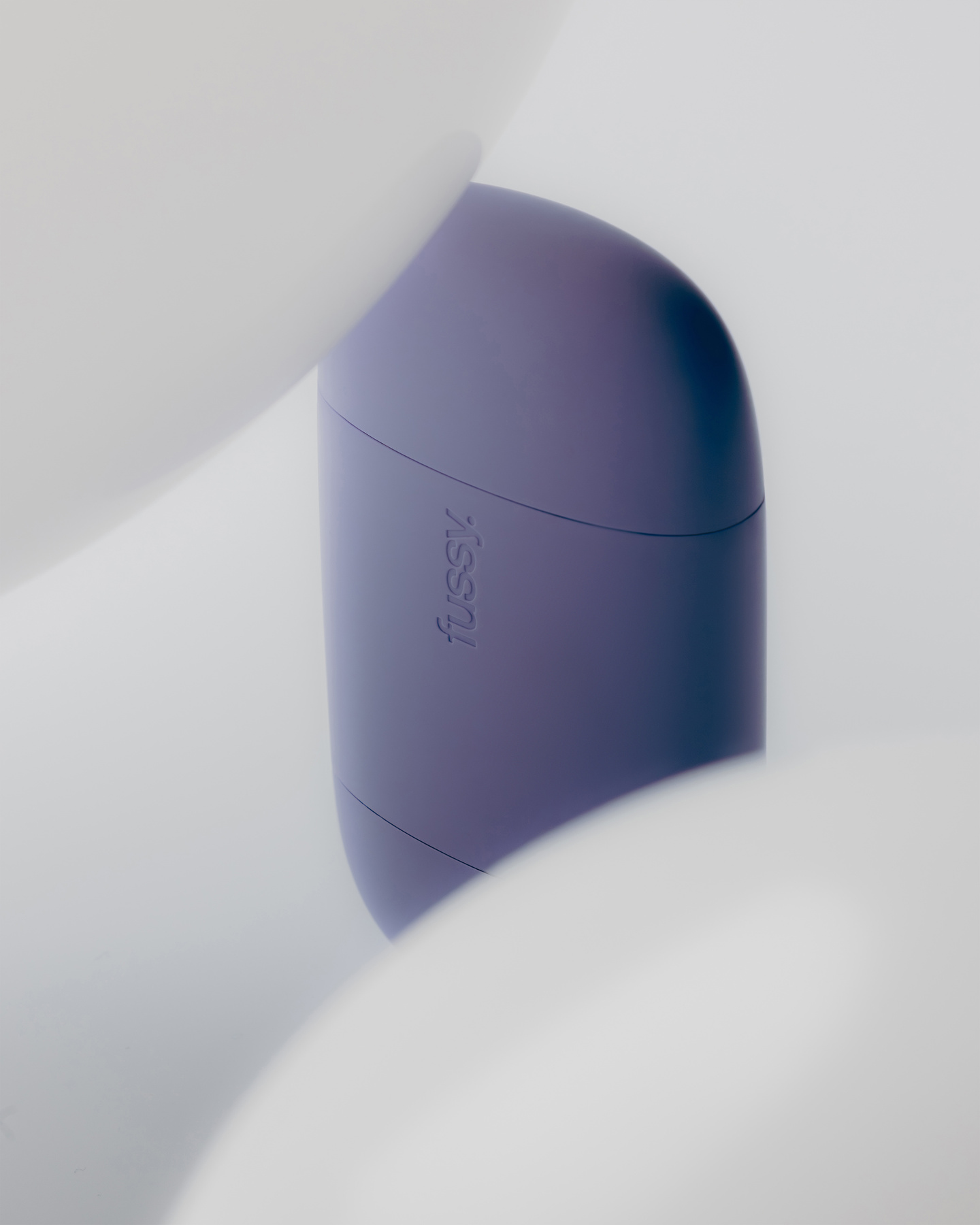 Small purple Fussy deodorant case set between soft white spherical shapes.