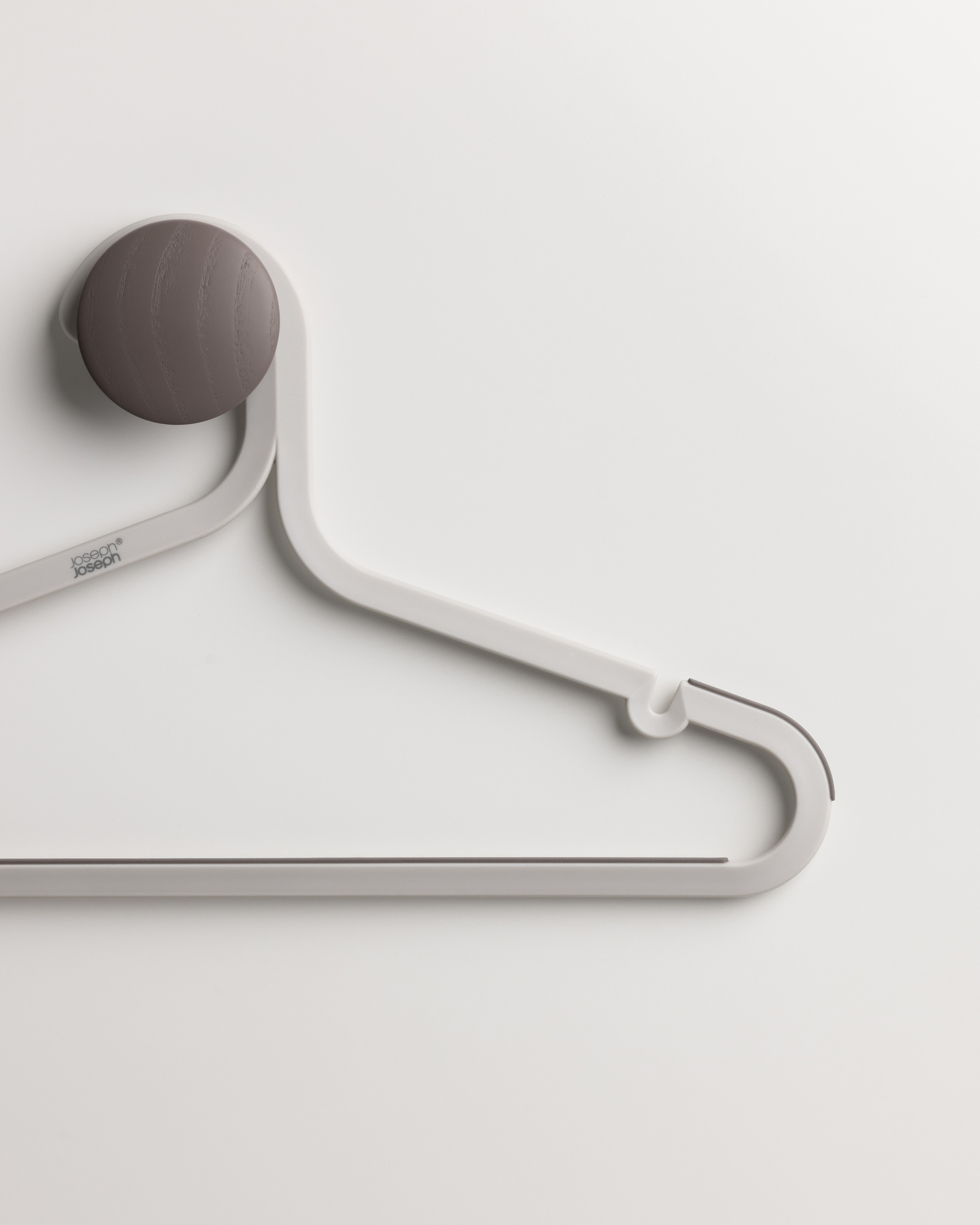 Single grey coat hanger hanging from a round wooden wall hook