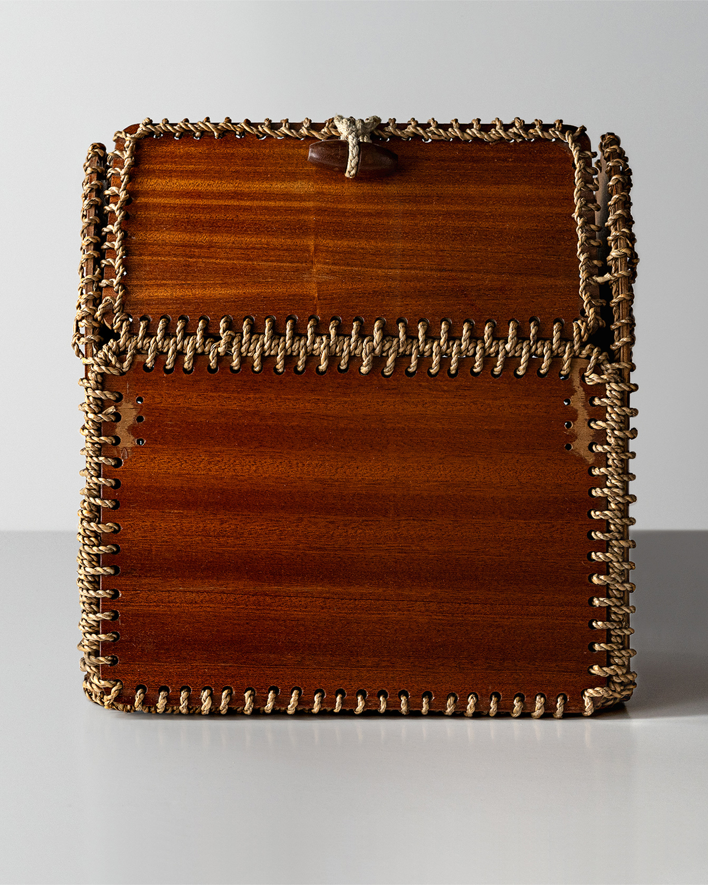 Small textured brown box resting on a white display plinth against a light background.